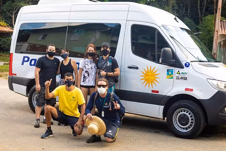 Adventure group posing by a Paraty Tours van, ready for their exciting journey to Sono Beach.