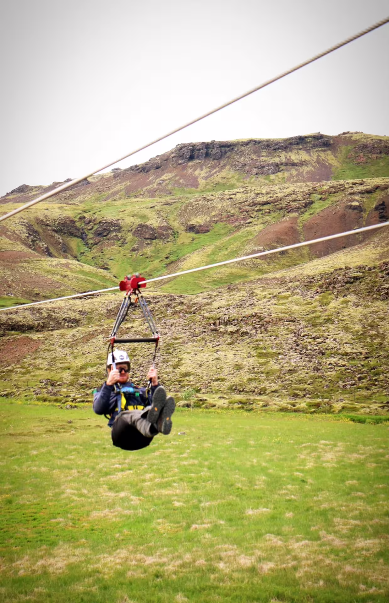 Adventure seeker enjoying a thrilling zipline ride over lush green hills, capturing the essence of freedom and excitement.