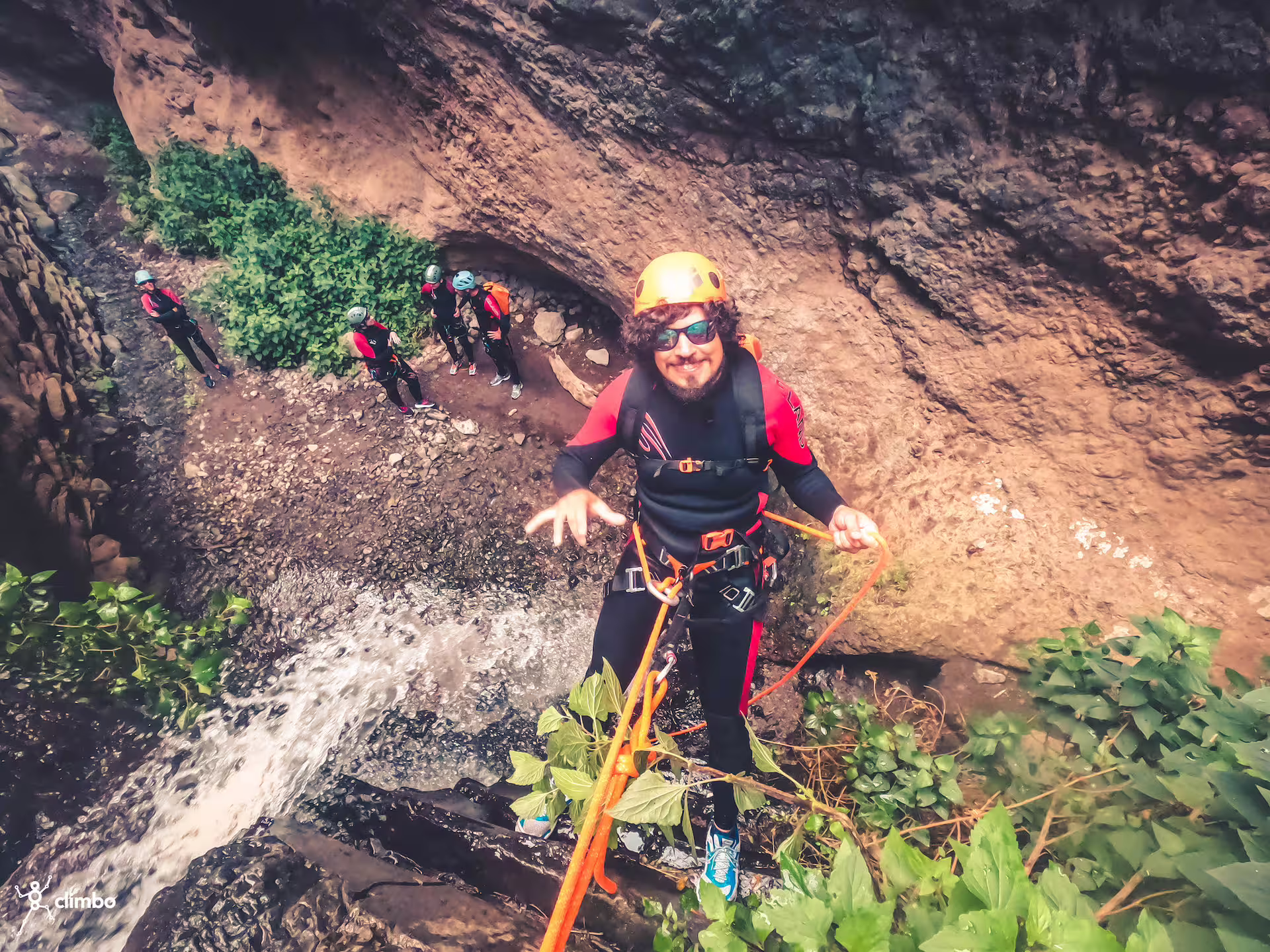Adventurer abseiling down a waterfall in the rainforest, showcasing canyoning gear and lush natural surroundings.