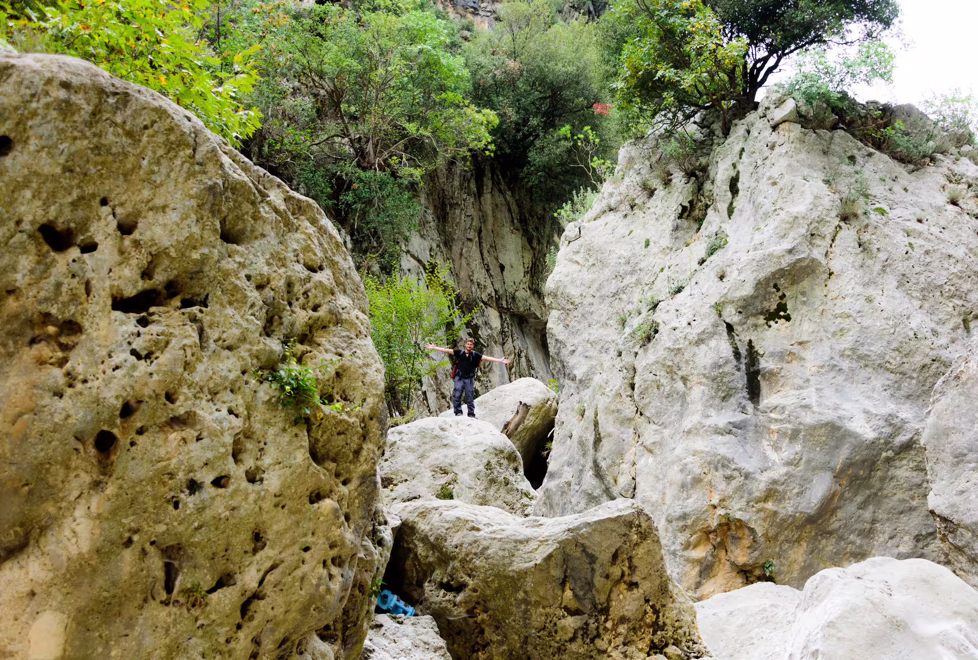 Adventurer standing on huge limestone boulders in Ridomo Gorge, a scenic guided hike in the Mani region