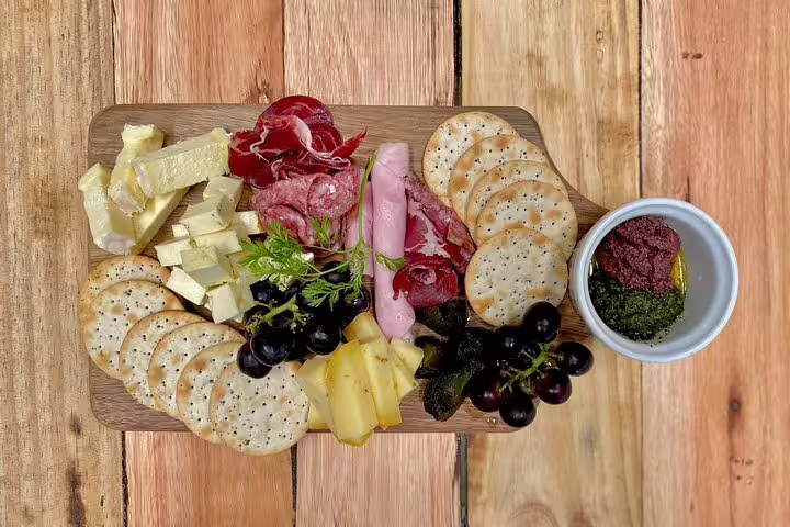 Delicious charcuterie board with assorted cheeses, meats, crackers, grapes, and dips on a wooden table in Africa.