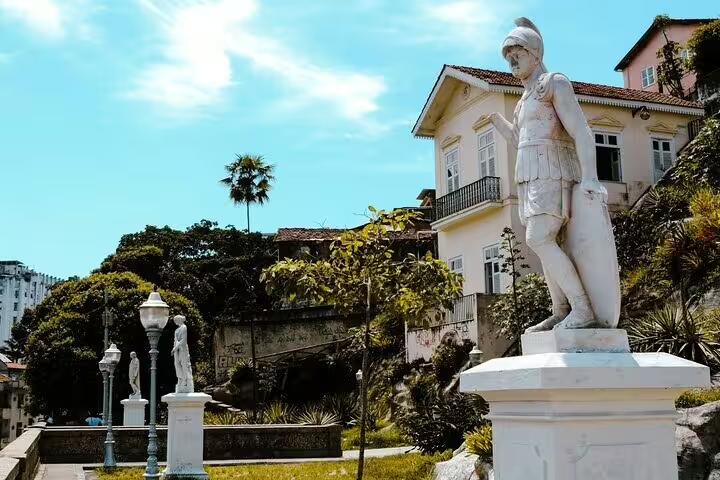 Historic statue and charming architecture in a lush garden setting, highlighting Afro-Brazilian culture in Rio.