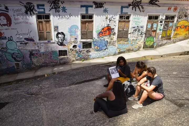 Tour guide discussing Afro-Brazilian history with visitors against a backdrop of colorful graffiti in Rio's Little Africa.