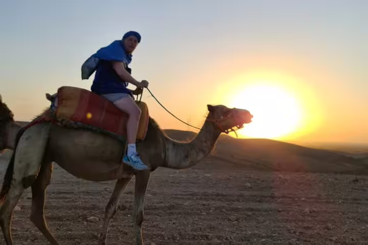 Rider on camel during Agafay Desert sunset camel ride tour from Marrakech, panoramic views and warm light