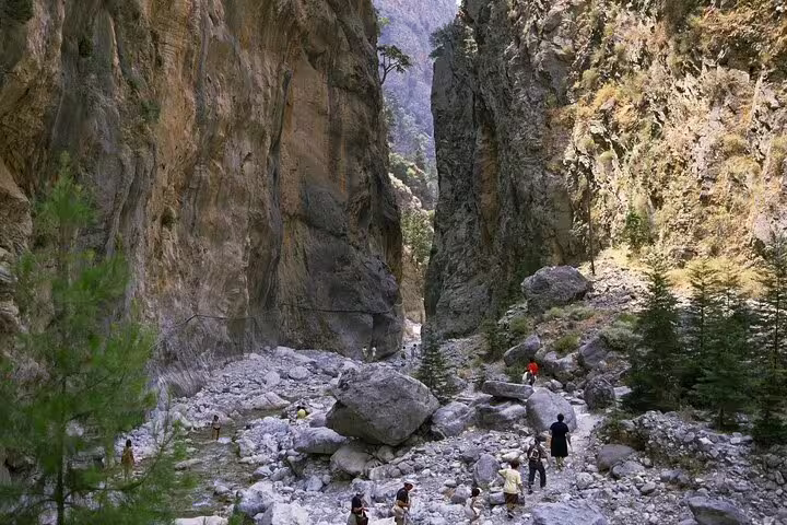 Hikers explore the rugged terrain of Agia Irini Gorge, surrounded by towering rock formations and lush greenery.