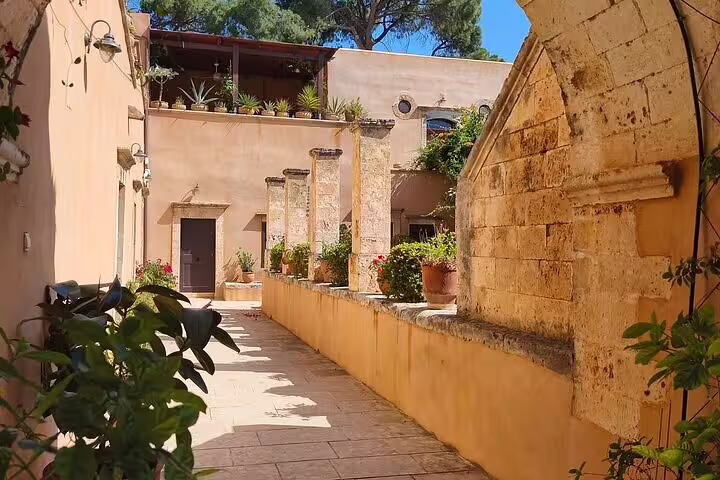 Serene courtyard of Agia Triada Monastery, showcasing historic architecture and lush greenery in Chania, Crete.