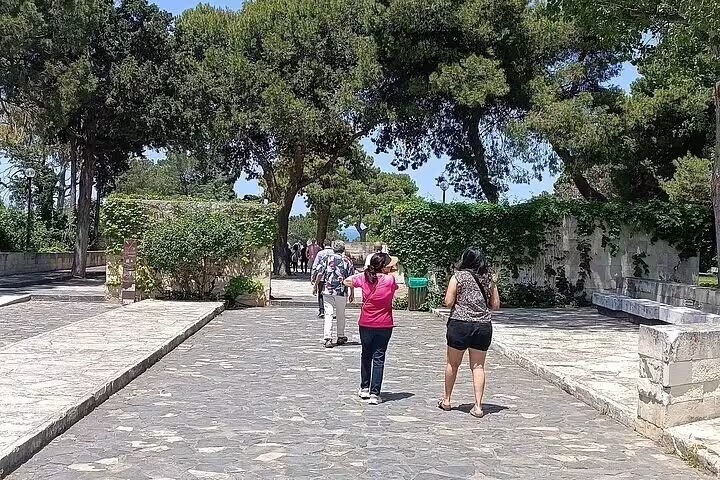 Visitors strolling through the lush gardens of Agia Triada Monastery, enjoying a guided tour in Chania's natural beauty.