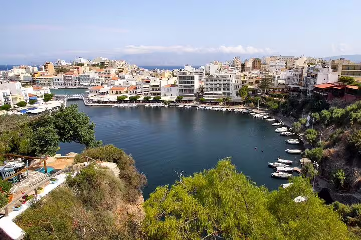 Scenic view of Agios Nikolaos with its charming lake, white buildings, and boats under a clear blue sky.