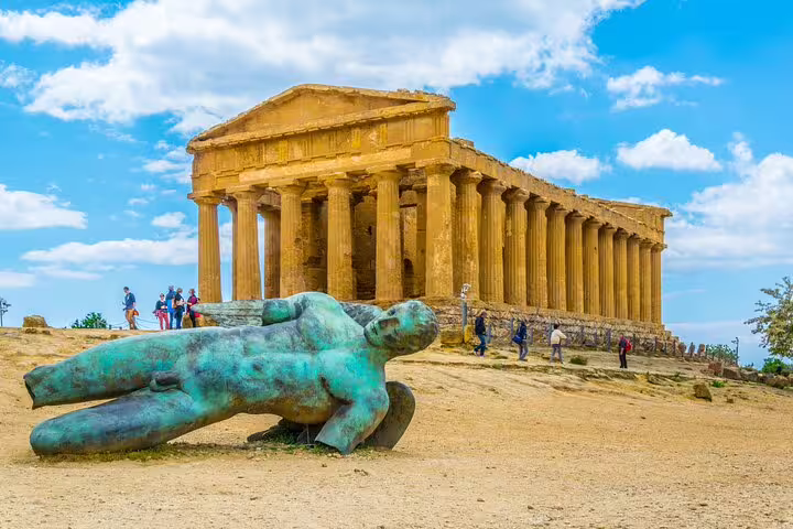 Tourists exploring the Temple of Concordia and bronze fallen Icarus statue on a private Valley of the Temples tour in Agrigento