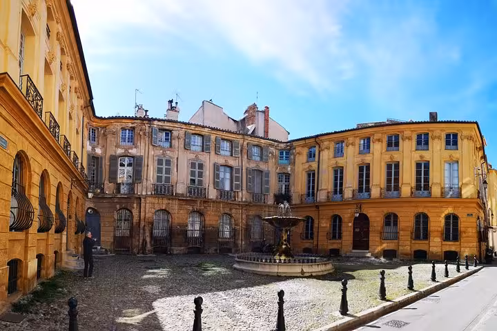 Historic Aix-en-Provence courtyard with fountain and pastel facades, featured on full-day Aix, Cassis and Marseille trip