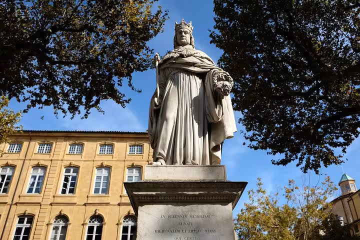 Statue of a historical figure in a sunlit square surrounded by classic architecture in Aix-en-Provence.
