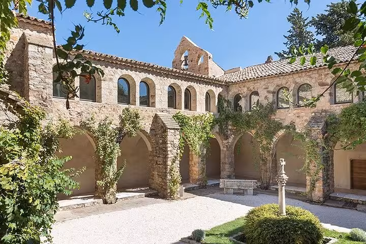 Historic courtyard of a stone monastery in Provence with arched walkways and greenery, a must-see on cultural tours.