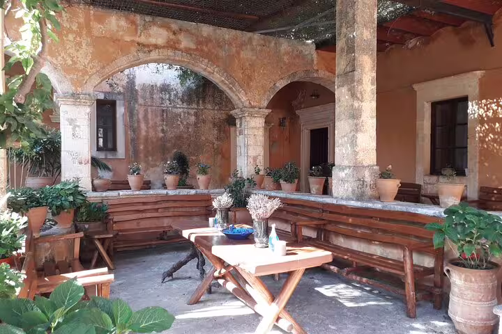 Charming rustic courtyard with wooden seating and potted plants on the Akrotiri Peninsula hiking tour.