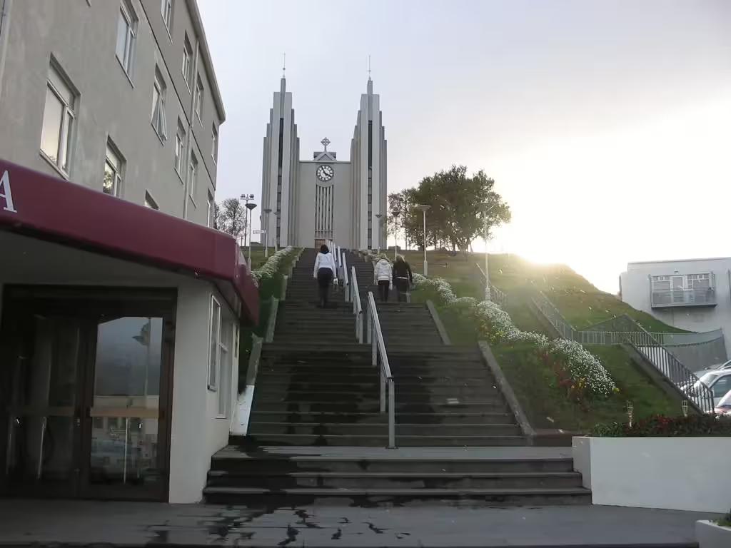 Stairs leading up to Akureyri Church with visitors climbing toward the modern concrete towers at sunset