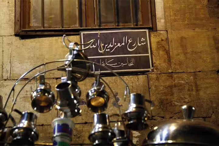Arabic Al Moez Street sign with traditional metal teapots in Khan El Khalili on Cairo night tour