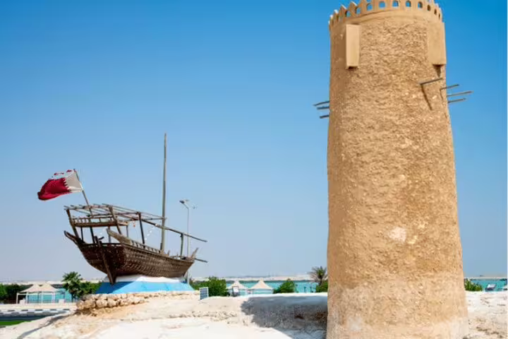 Historic dhow and traditional tower at Al Zubarah, Qatar, highlighting cultural heritage on a North Qatar tour.