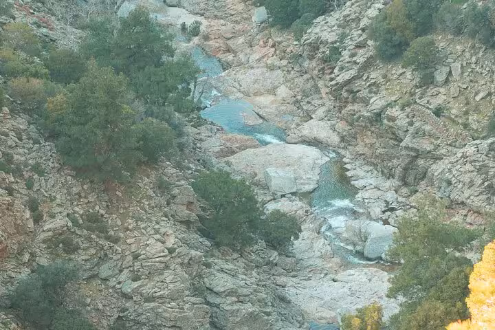 Rocky gorge with turquoise pools and flowing stream along the Alama Spring hiking trail in Ikaria, Greece