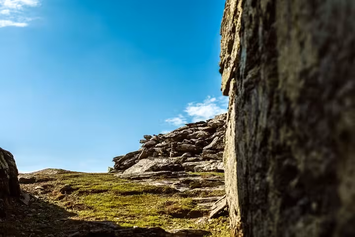Rocky mountain path with grassy slope and blue sky on Ikaria Hike: Alama Spring, ideal for scenic Aegean trekking