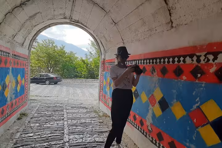 Traveler exploring a vibrant tunnel with colorful murals in Albania, highlighting cultural art on a scenic road trip.