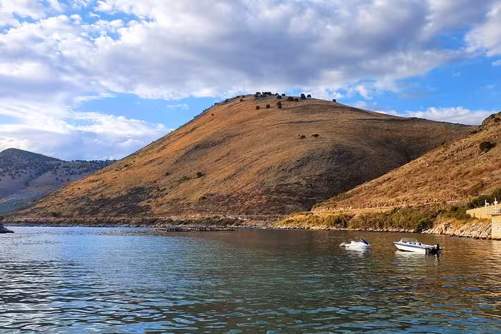 Scenic view of Albanian hillside and tranquil waters with boats, ideal for a private guided tour experience.