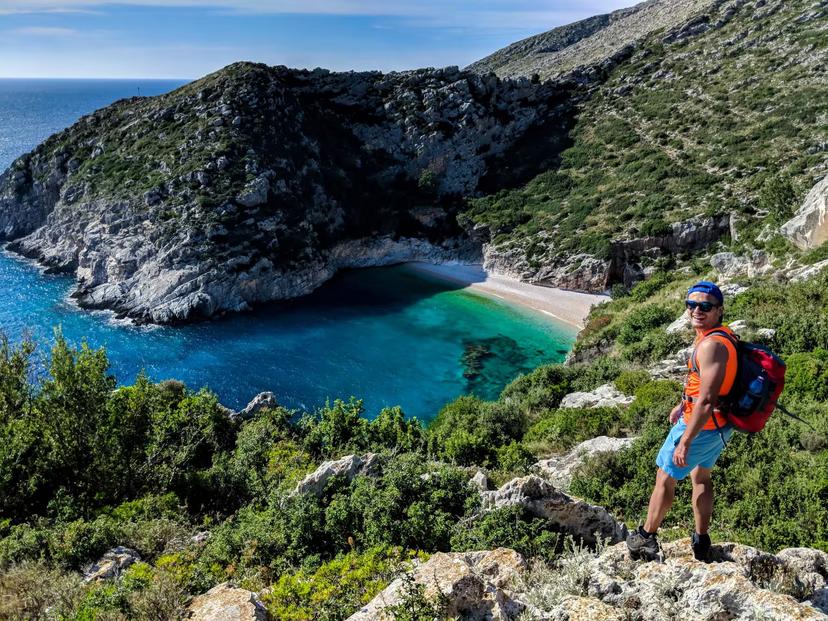 Hiker overlooking a secluded cove with turquoise waters on the Albanian Riviera, perfect for adventure seekers.