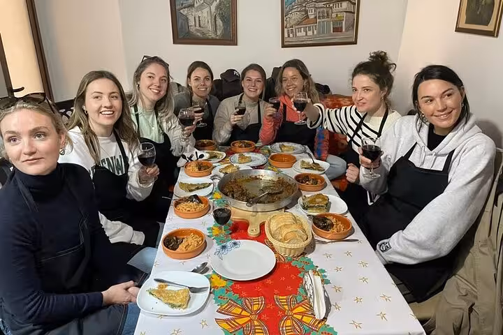 A group of friends toast with wine around a table laden with traditional Albanian dishes on a cultural tour.