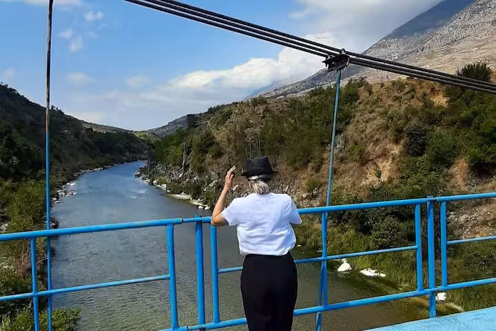 Traveler admiring the serene river and mountain views from a bridge in Albania on the Albanian Highlights 6-day tour.