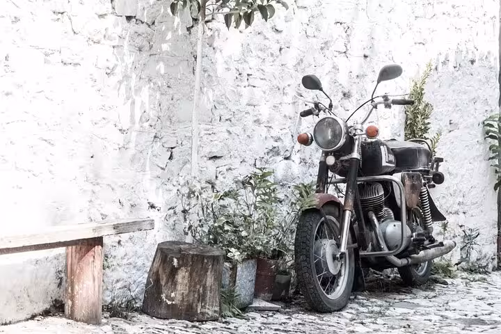 Discover the rustic charm of Albanian villages with vintage motorcycles and quaint stone benches on a private tour.