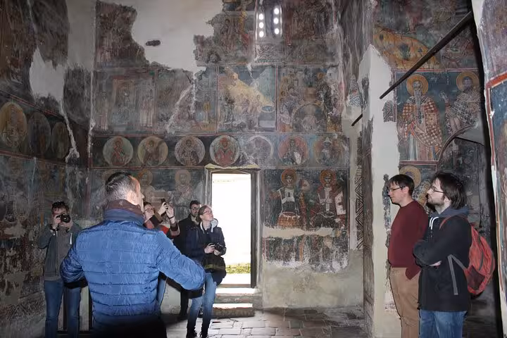 Visitors explore ancient frescoes in a historic Albanian church, showcasing the rich cultural heritage of Albania tours.