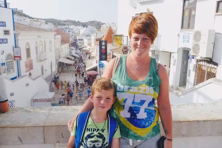 Tourists enjoy a scenic view from a balcony overlooking the bustling streets of Albufeira during a guided city walk.
