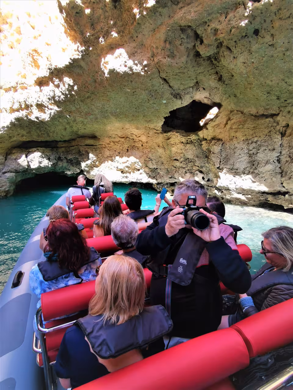 Guests on a private Albufeira boat charter photographing Algarve sea caves and turquoise water on a coastline cruise