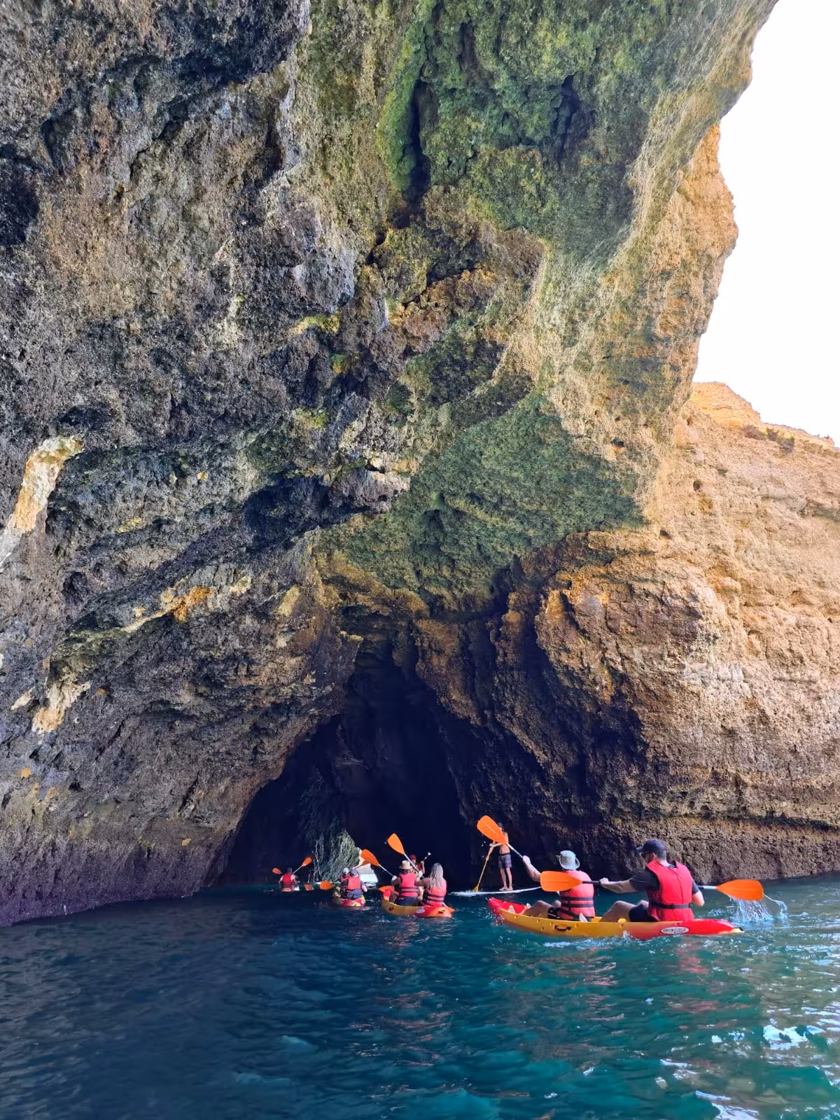 Group of kayakers entering a stunning Albufeira sea cave arch on a full experience private kayak tour