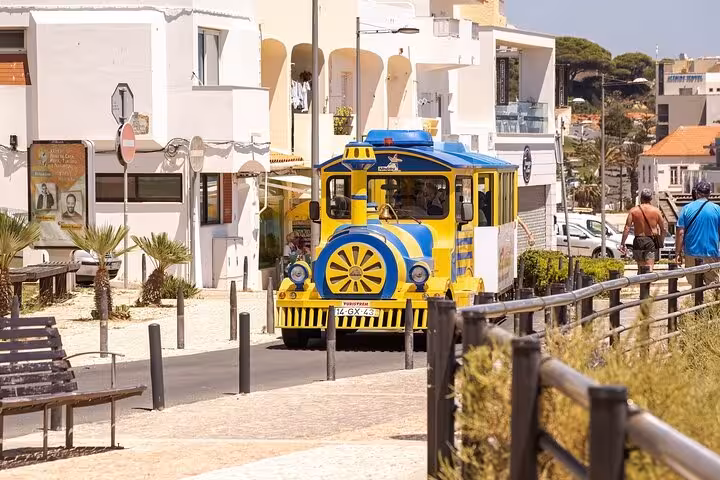 Colorful tourist train passing through Albufeira streets, perfect for exploring the city during a guided tour.