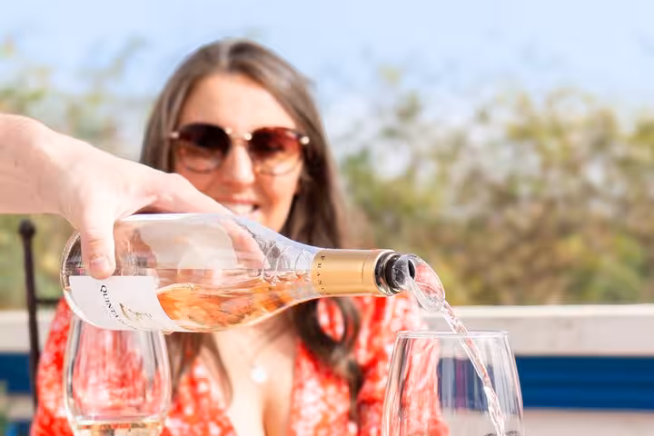 A woman enjoys wine tasting under the Algarve sun during a full-day tour from Albufeira.
