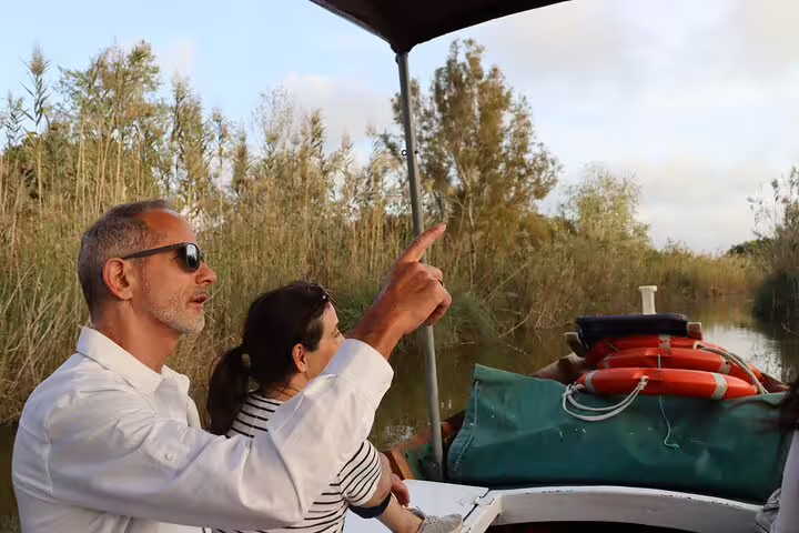 Couple enjoying a serene boat ride through lush Albufera wetlands during a private day trip with paella and nature trek.