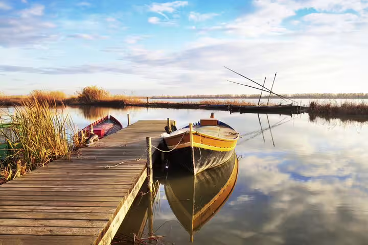 Scenic view of Albufera lagoon with traditional wooden boats and serene landscape, perfect for a private day trip with paella and nature trek.