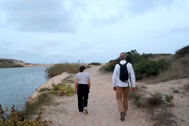 Two people walking along a scenic path by the water during a Private Albufera Day Trip with nature trek experience.