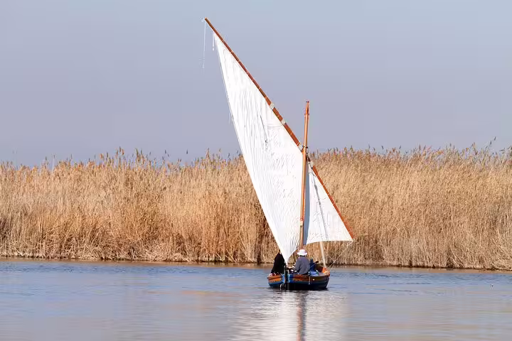 Sailboat gliding through Albufera's serene waters during a private day trip with paella lunch, boat ride, and nature trek.