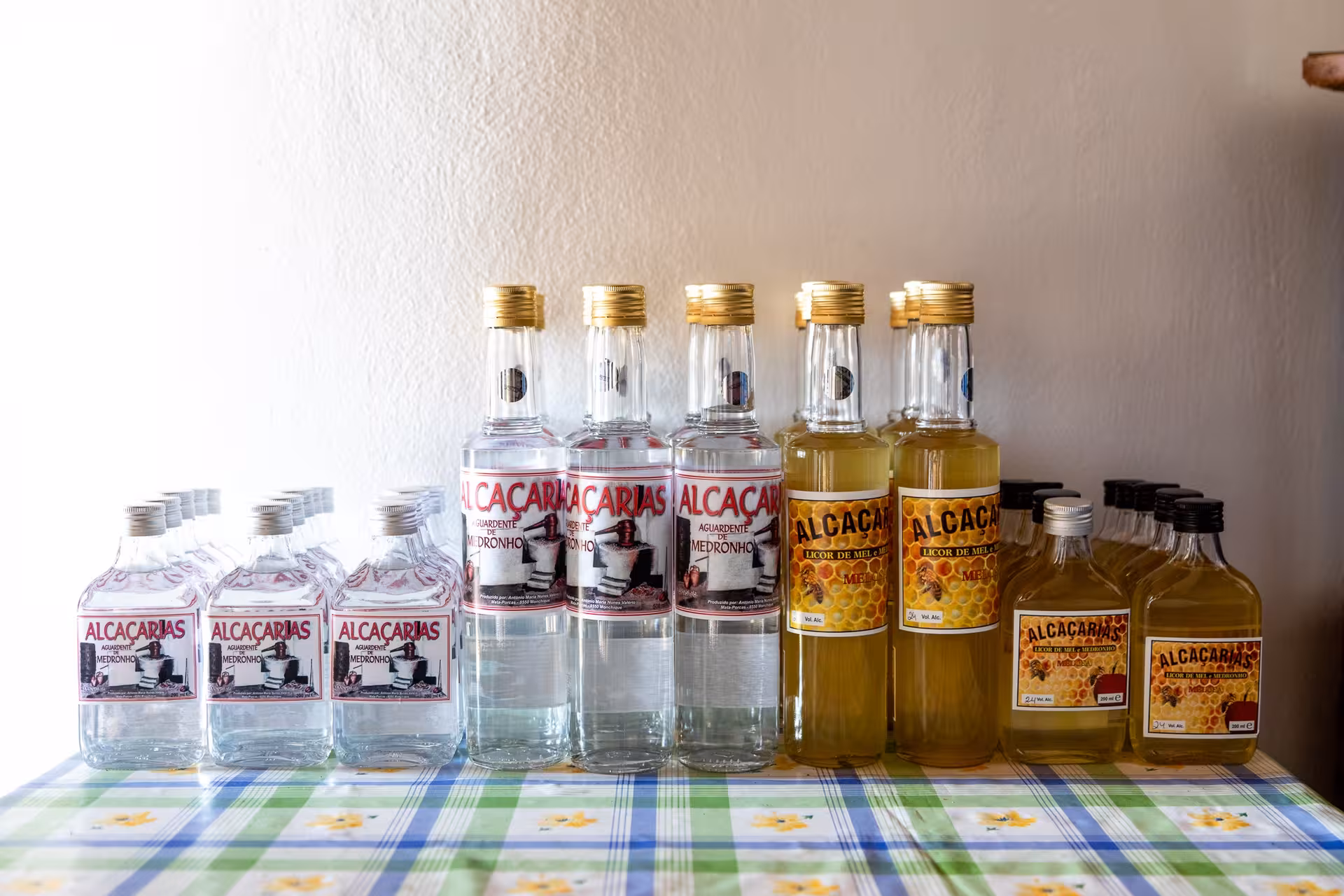 Display of Alcacarias medronho brandy and honey liqueur bottles on a table during a Super Dia Algarve tasting stop