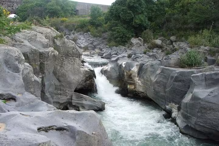 Rushing waters of Alcantara River carving through ancient volcanic rocks on the Etna and Alcantara tour.