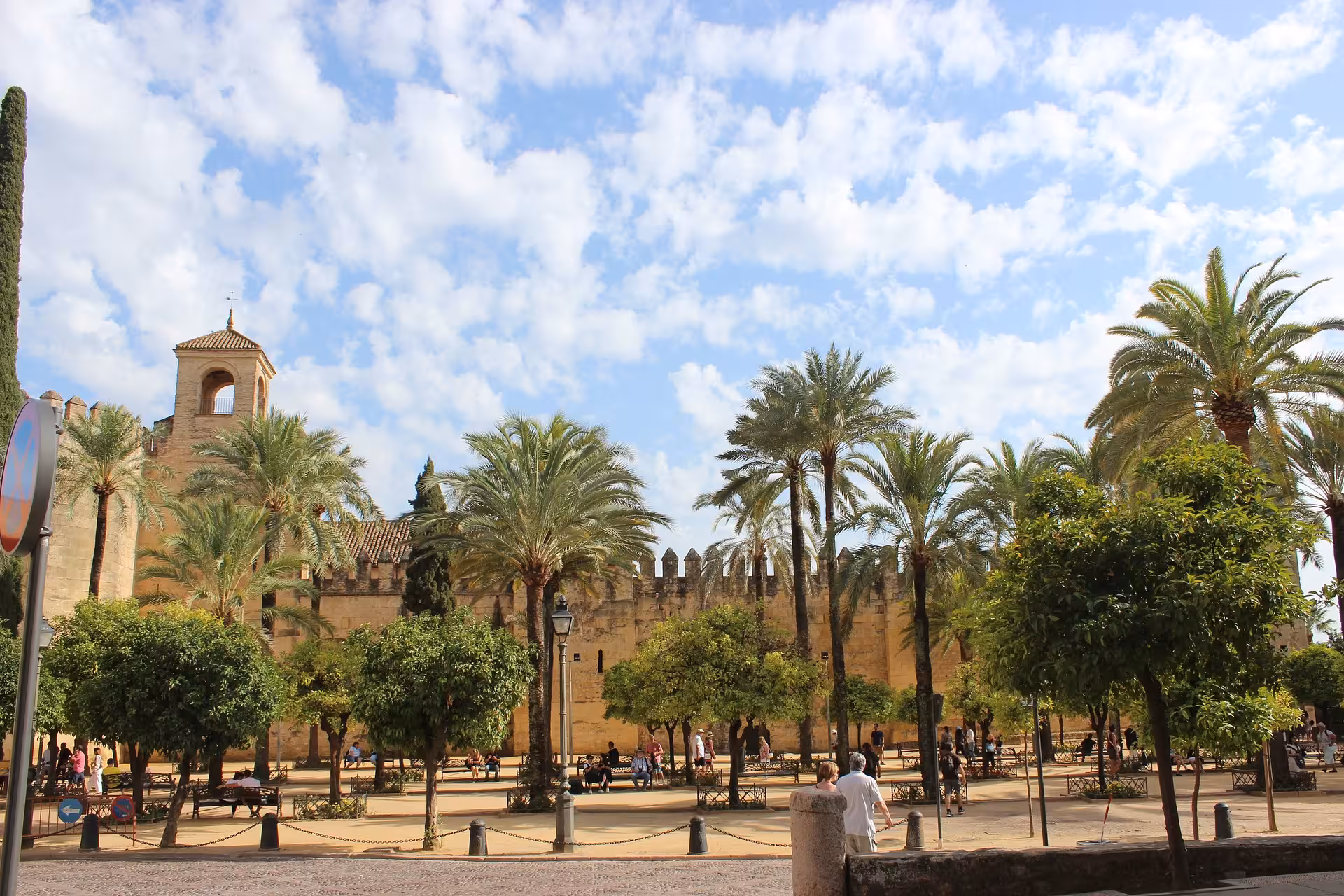 View of the Alcázar of the Christian Monarchs with palm trees and blue skies, perfect for a cultural tour.