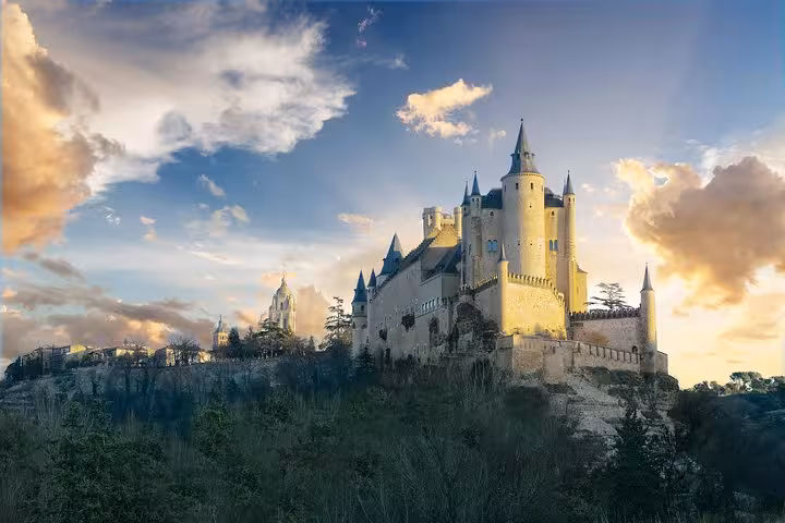 Majestic Alcázar of Segovia illuminated at sunset, a highlight of the El Escorial, Valley & Segovia tour from Madrid.