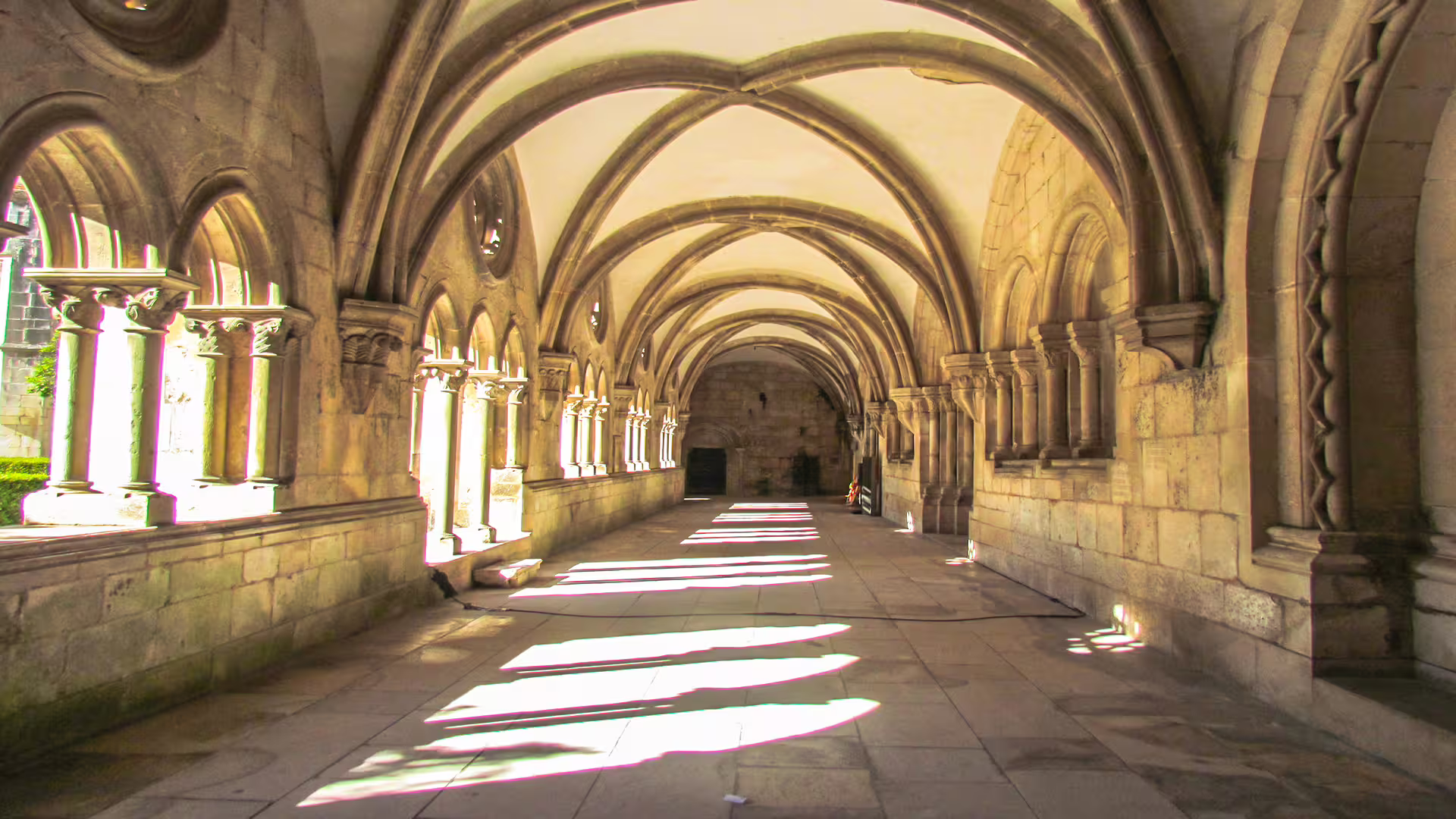 Sunlit Gothic cloister inside Alcobaça Monastery, showcasing intricate arches on a private tour to Nazaré and Alcobaça.