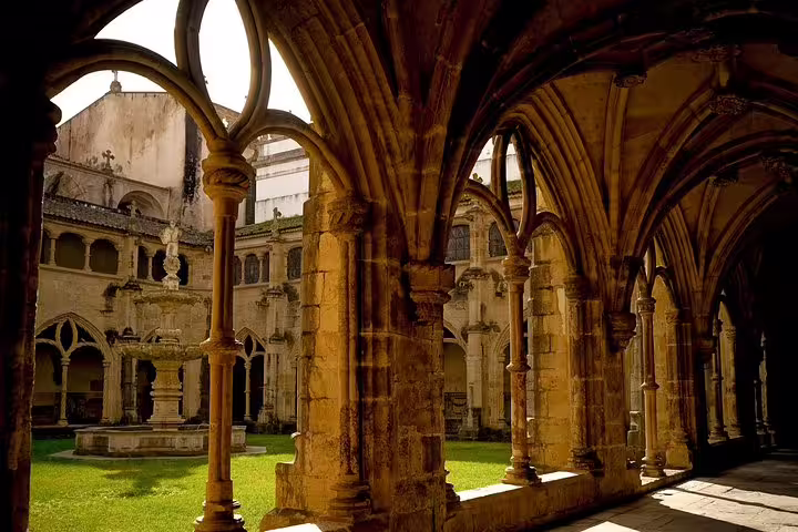 Gothic cloisters of Alcobaça Monastery with ornate arches and sunlit courtyard, part of Óbidos, Nazaré, Batalha, Fatima tour.