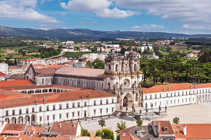 Aerial view of the historic Alcobaça Monastery surrounded by lush landscapes on the Obidos and Nazaré tour.