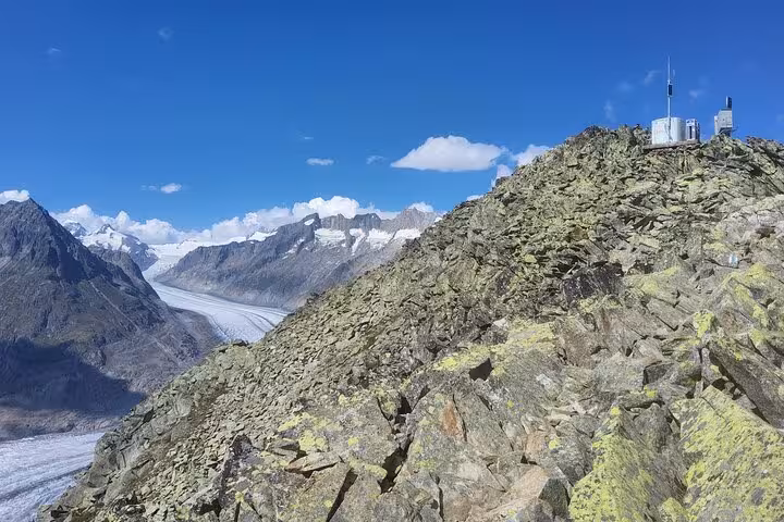 Viewpoint above the Aletsch Glacier on a Zurich day tour, rocky ridge and Jungfrau Alps under blue sky