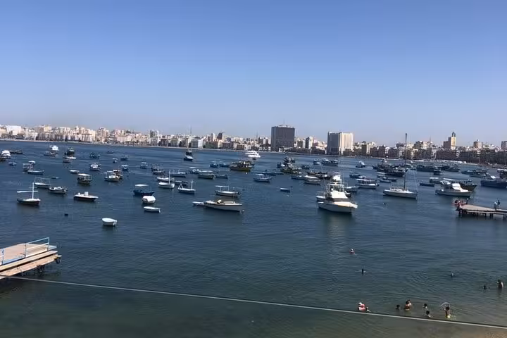 Alexandria Corniche waterfront with boats and skyline, scenic stop on private day tour from Cairo