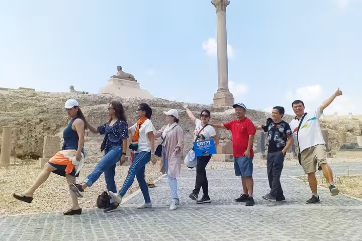 Tour group posing at Pompey’s Pillar on a private Alexandria day trip from Cairo with lunch and transfers