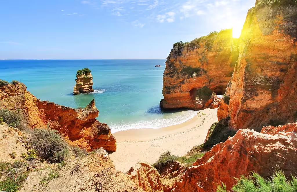 Golden cliffs and turquoise waters at a secluded Algarve beach, highlighting the stunning landscapes of southern Portugal tours.