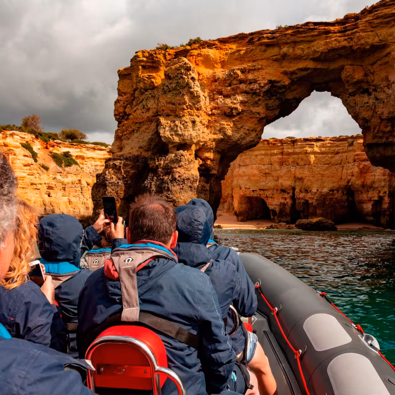 Guests in a RIB approaching the Algarve sea cave arch on a Benagil caves and dolphins boat tour in Portugal